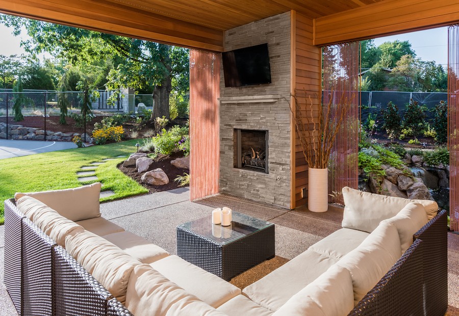 outdoor seating area with a couch, ottoman, fireplace, and wall-mounted outdoor TV