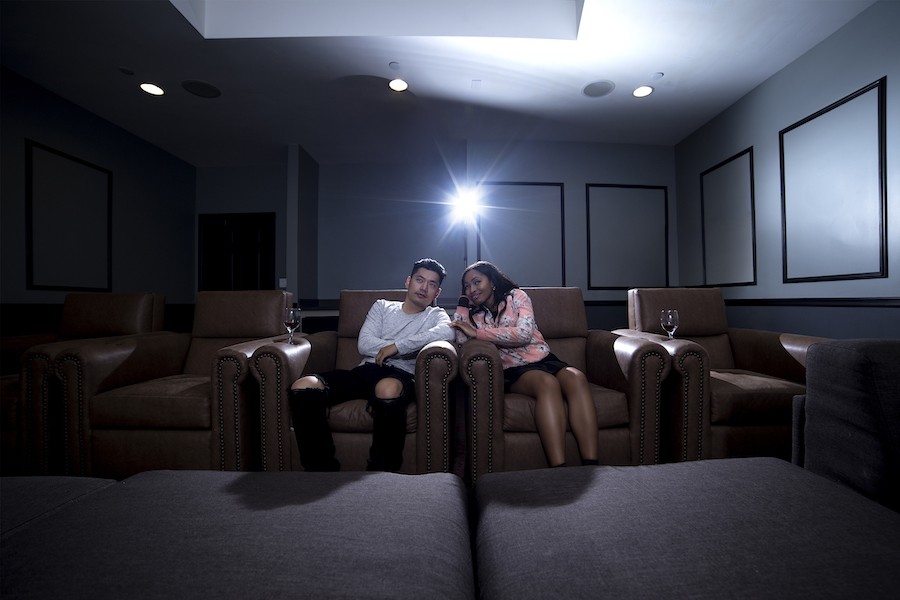 A couple enjoys a movie in their home theater installation.