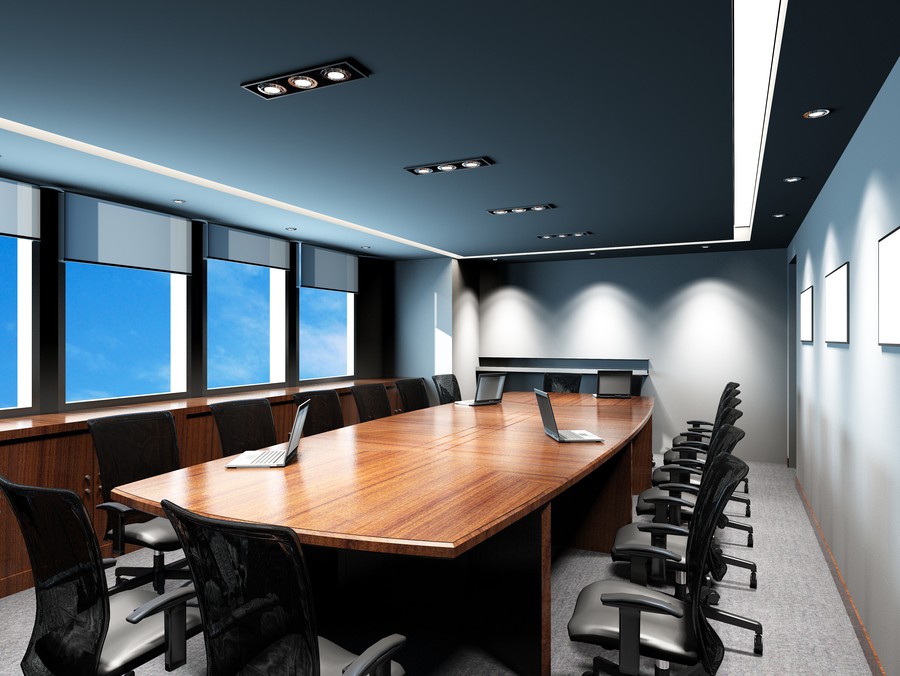 A boardroom with a table, motorized shades, and in-ceiling lights,