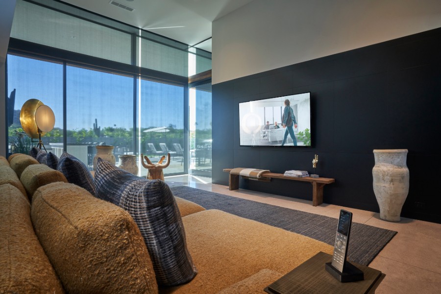 Stylish living room featuring a large TV, a plush couch, and smart shades.