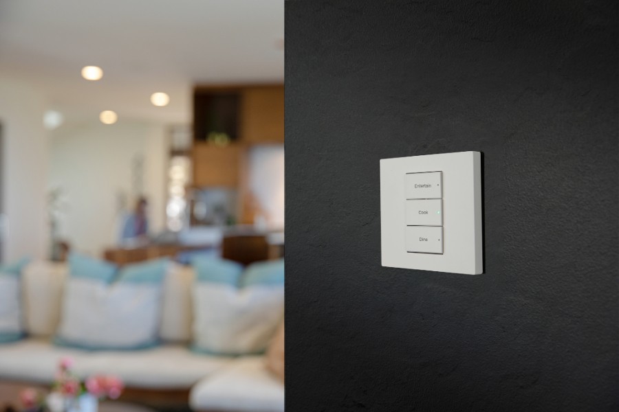 A white light keypad mounted on the wall in a living room, controlling the room's lighting.