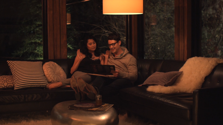 A couple relaxes on a couch in a room with warm evening tones, creating a cozy atmosphere.